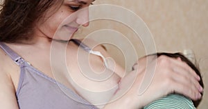 Mother breastfeeding baby at home. Motherhood and maternity care concept. Cheerful mom enjoy breastfeeding