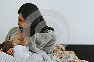 Mother breastfeeding her baby on the bed