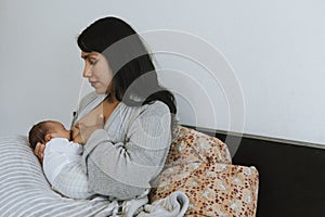 Mother breastfeeding her baby on the bed