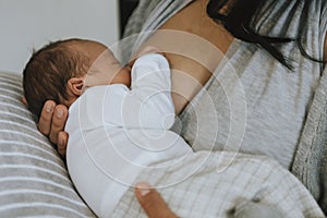 Mother breastfeeding her baby on the bed