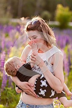 Mother breastfeeding her baby in a field of purple flowers.