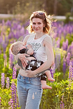 Mother breastfeeding her baby in a field of purple flowers.