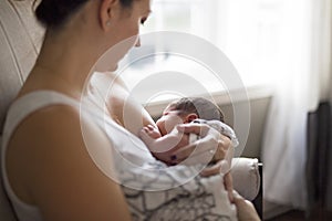 Mother breastfeeding her little baby boy in arms.