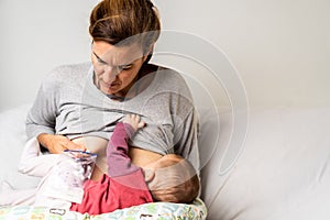 Mother breastfeeding her newborn baby while pumping milk from her other breast to store it in a special breastfeeding bag