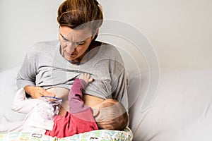 Mother breastfeeding her newborn baby while pumping milk from her other breast to store it in a special breastfeeding bag photo