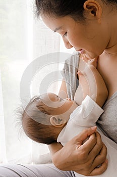 Mother breastfeeding her newborn baby beside window