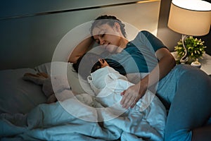 mother is breastfeeding a infant baby while lying and sleeping on bed at night