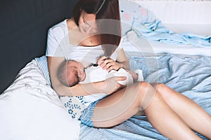 Mother breastfeeding newborn baby at home.