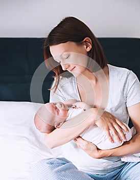 Mother breastfeeding newborn baby at home.