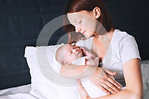 Mother breastfeeding newborn baby at home.