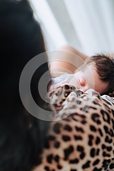 Mother breastfeeding newborn baby at home, loving mom feeding baby breast milk