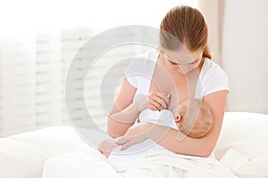 Mother breastfeeding newborn baby in white bed