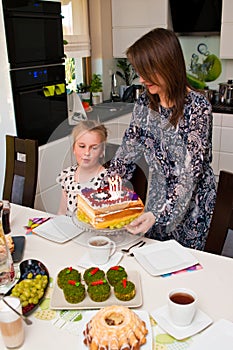 Mother bringing birthday cake for her lovely daughter