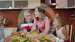 Mother brings baked chicken dish from oven at family thanksgiving birthday celebration in kitchen. friends greeting