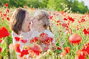 Mother brunette in white with daughter together on blossoming red poppies field