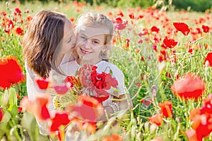 Mother brunette in white with daughter together on blossoming red poppies field