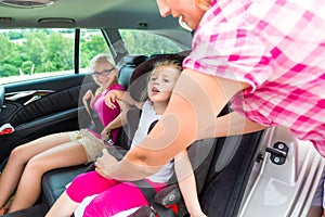 Mother buckling up on child - car safety seat photo