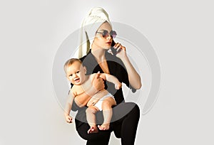 Mother business woman and her baby child in studio. Loving mom working with her child. Portrait of busy mum mother