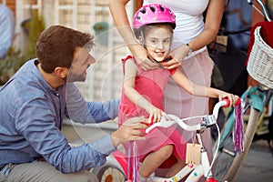 Mother buying at happy girl bicycle helmet in bike shop