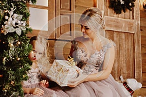 Mother calming down her sad crying infant daughter standing by Christmas tree