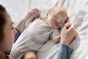 Mother Care. Loving Mommy Holding Hands Of Her Adorable Sleeping Newborn Baby