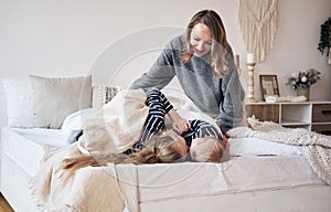 Mother care. Young mother covering children with a blanket in bedroom. Brother and sister embracing and sleeping on the bed.