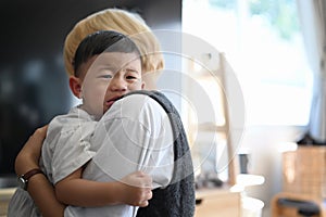 Mother caressing and calming down her crying baby son while standing at home.