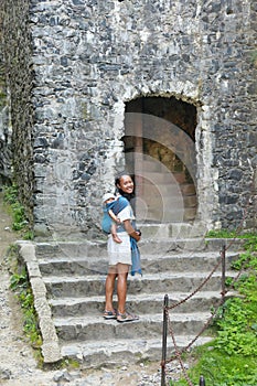 Mother carrying baby in sling and entering tower on Trosky Castle