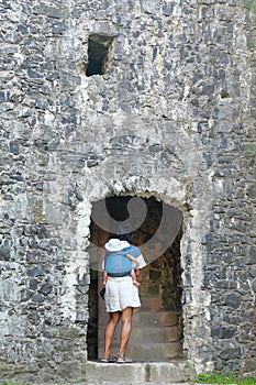 Mother carrying baby in sling and entering tower on Trosky Castle