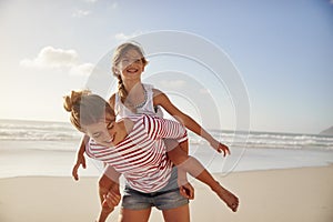 Mother Carrying Daughter On Shoulders On Beach Vacation