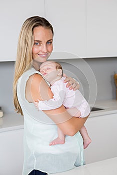 Mother carrying her baby in kitchen at home