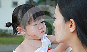 Mother carrying her little girl and crying in park