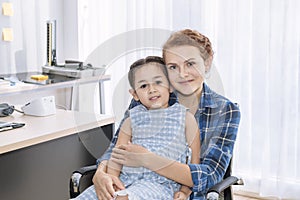 Mother Caucasian and kid smiling in hospital room.Waiting for doctor.