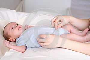 Mother changes diapers to her newborn baby, Little boy on changing table in clean dry nappy, Mom taking care of infant