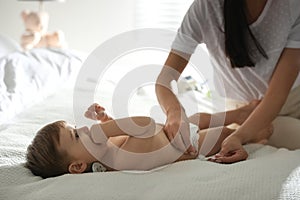 Mother changing baby`s diaper on bed