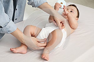 Mother changing baby`s diaper on bed at home, closeup