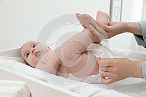 Mother changing baby`s diaper at home, focus on hands