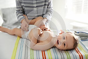 Mother changing baby`s diaper on table