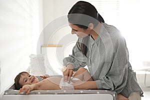 Mother changing baby`s diaper on table