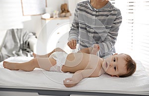 Mother changing baby`s diaper on table