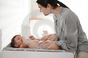 Mother changing baby`s diaper on table