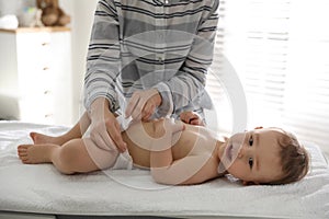 Mother changing baby`s diaper on table