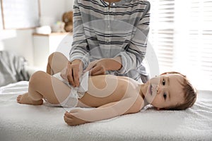 Mother changing baby`s diaper on table