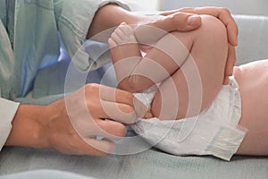 Mother changing baby's diaper on table, closeup