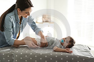 Mother changing baby`s diaper on table