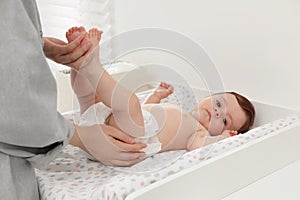 Mother changing baby`s diaper on table at home