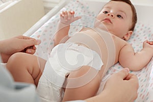 Mother changing baby`s diaper on table at home, closeup