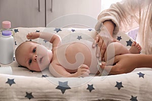 Mother changing baby\'s diaper on table indoors, closeup
