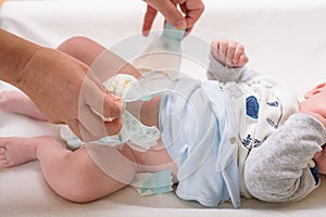 Mother changing diaper of adorable baby with a hygiene set for babies on the background