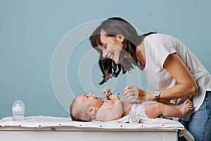 Mother changing diaper on her baby on table over blue background photo